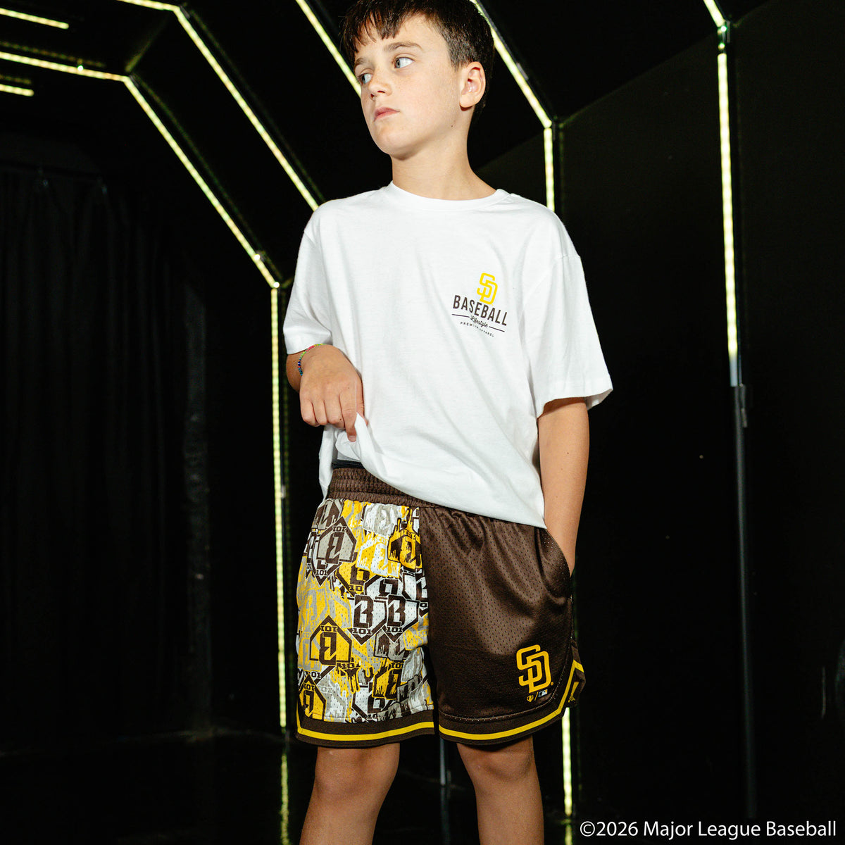 Youth model wearing youth shorts with "San Diego Padres Sticker Court" design