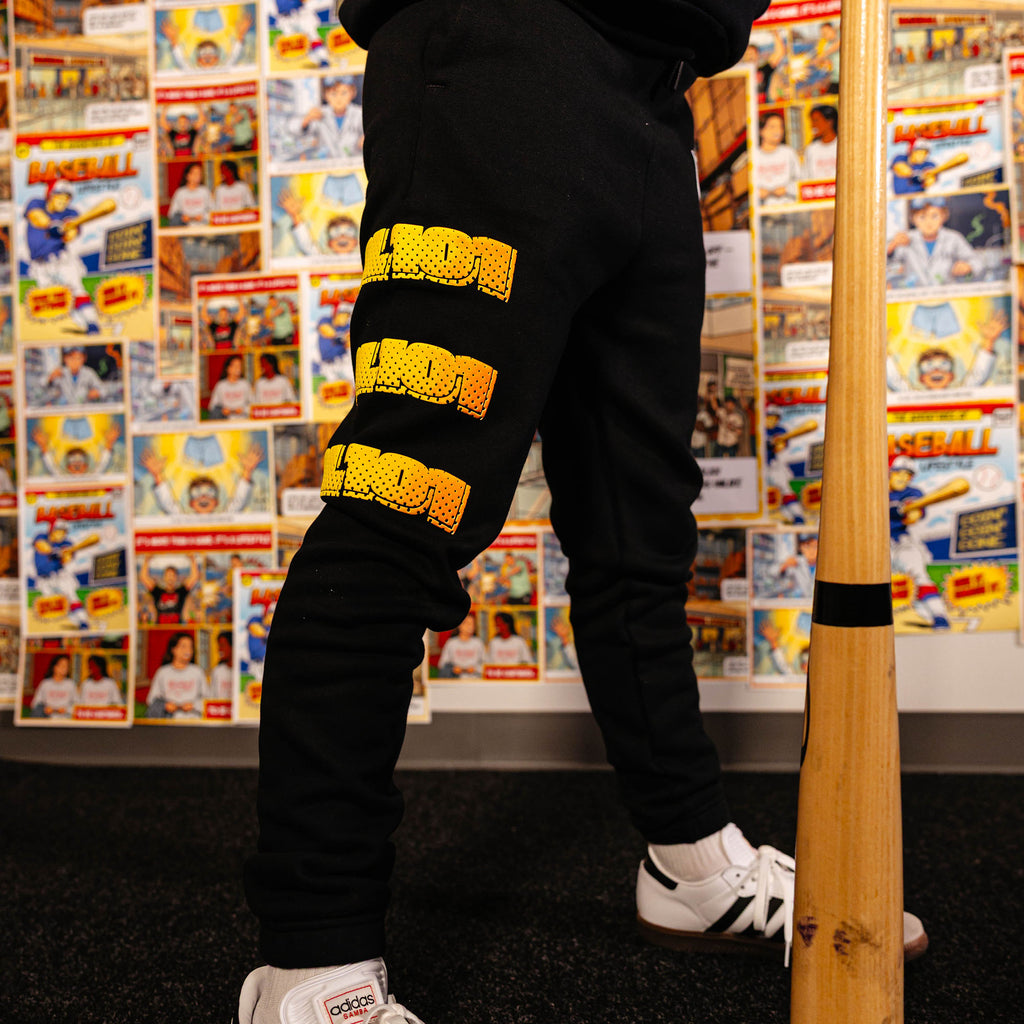 Youth model wearing black youth sweatpants with "Power Hitter" design