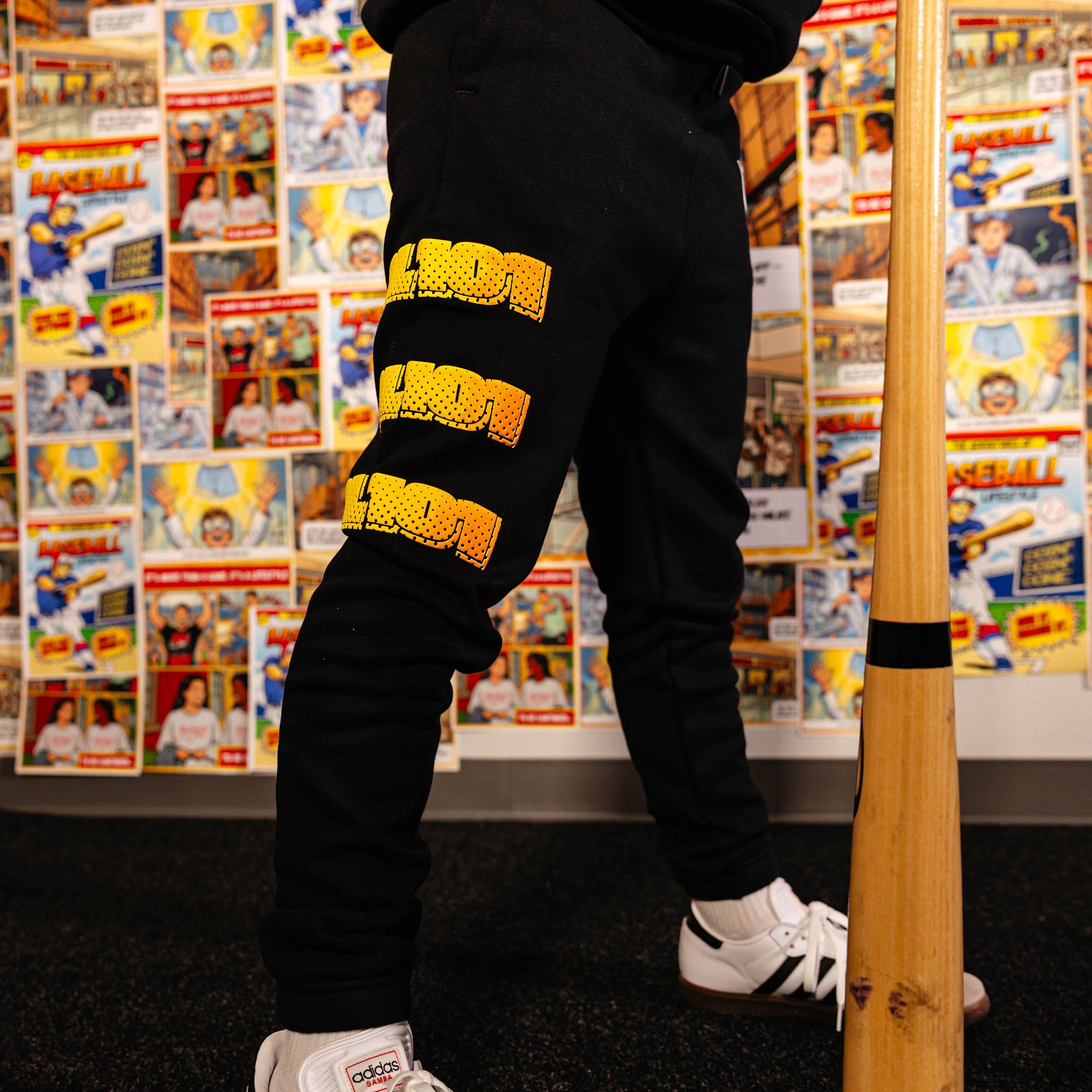 Youth model wearing black youth sweatpants with "Power Hitter" design