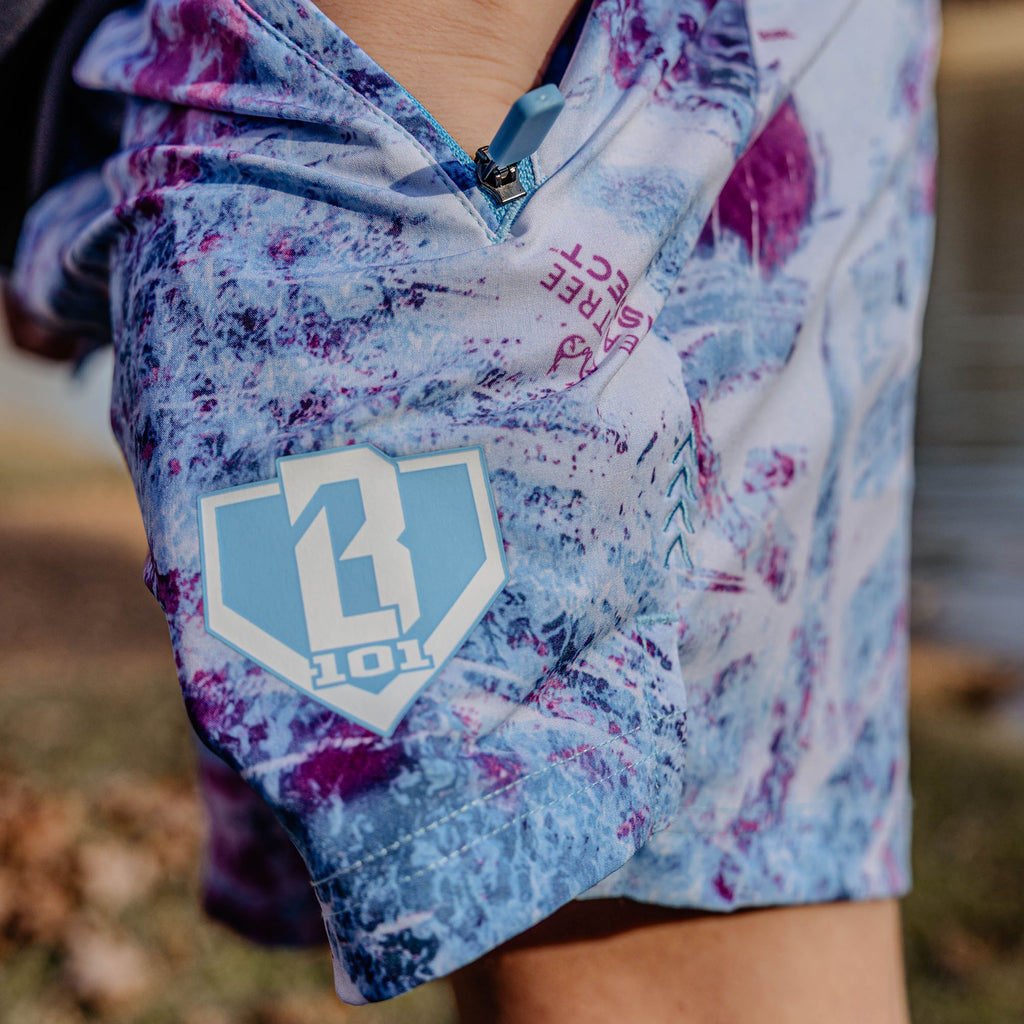 Close-up of blue and purple shorts with a BL101 logo on a blurred natural background