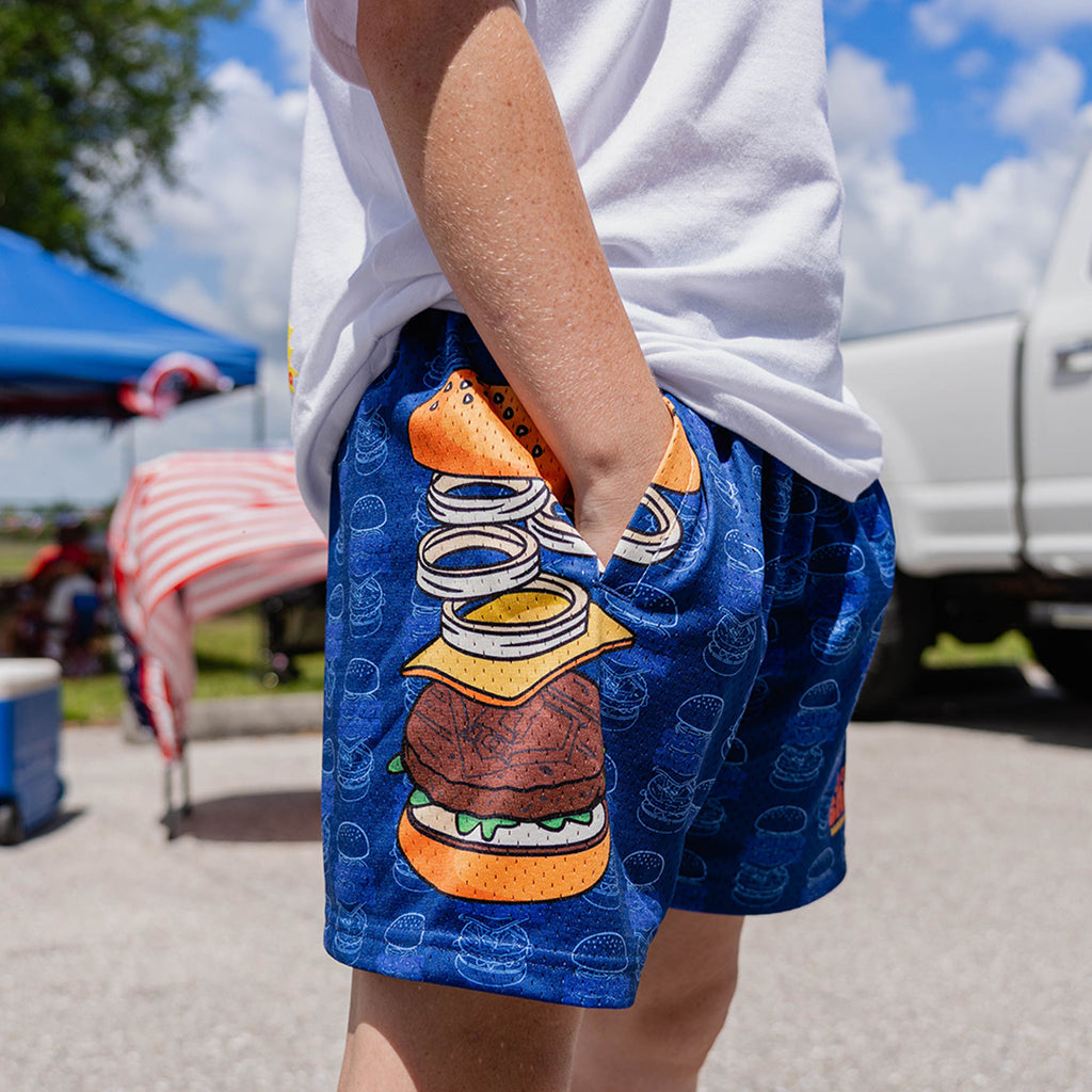 Lower body of male model wearing blue Secret Sauce burger print shorts