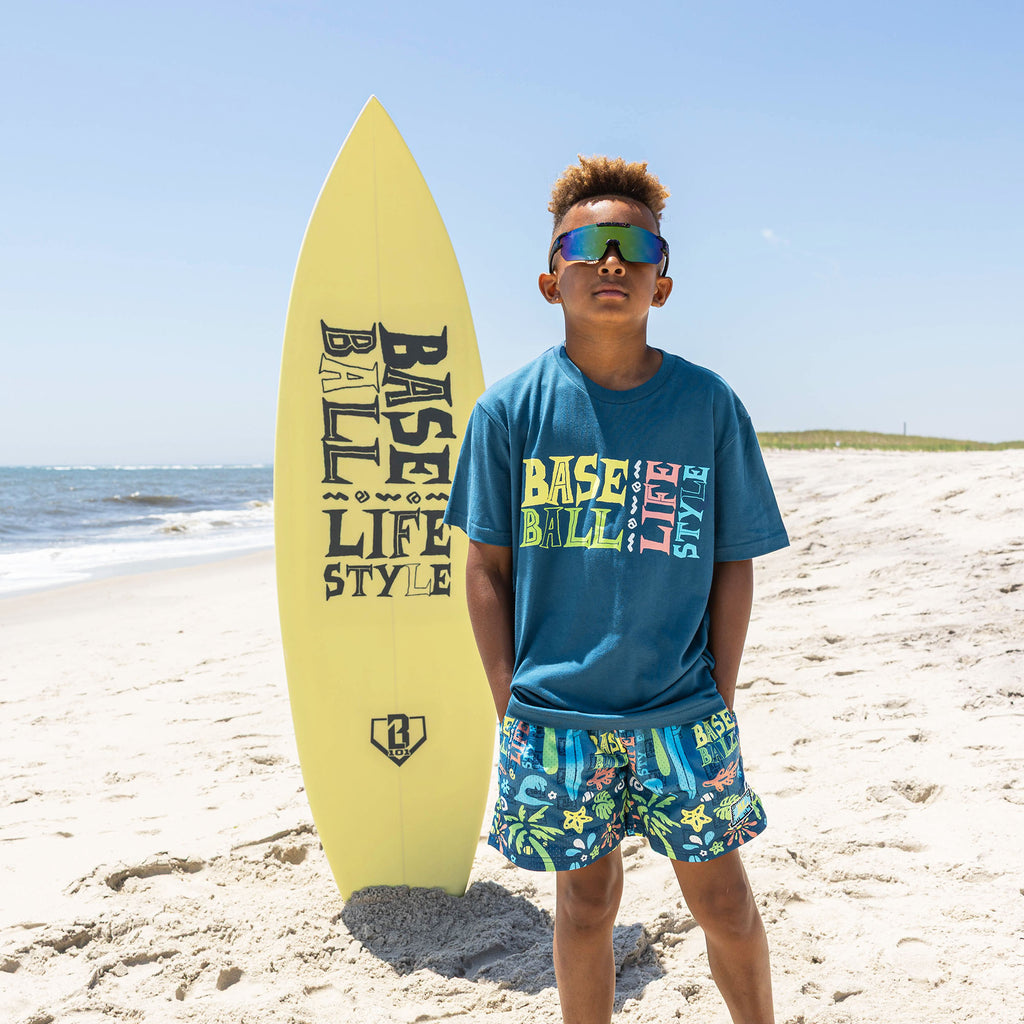 Youth model wearing blue youth graphic tee with "Surfside Slugger" design