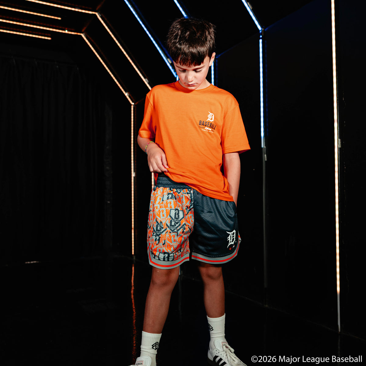 Youth model wearing navy youth shorts with "Detroit Tigers Sticker Court" design