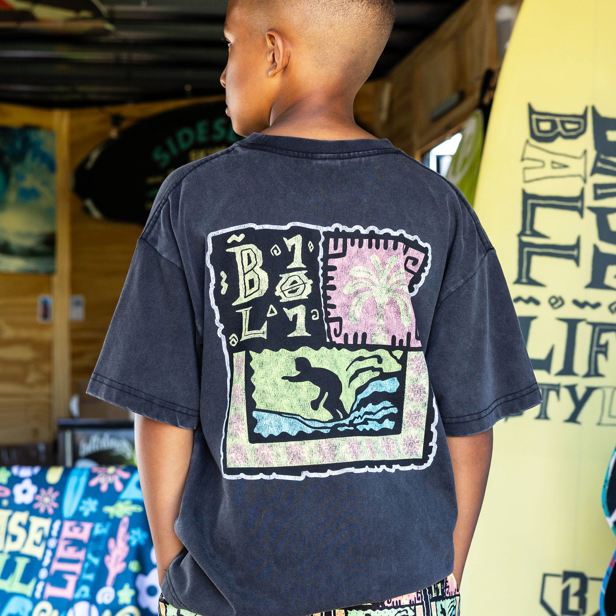 Youth model wearing black youth graphic tee with "Wave Goodbye" design