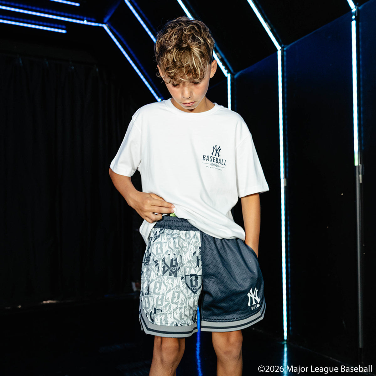 Youth model wearing navy youth shorts with "New York Yankees Sticker Court" design