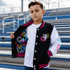 Child wearing a black, pink and white varsity jacket with colorful designs, standing in front of bleachers.