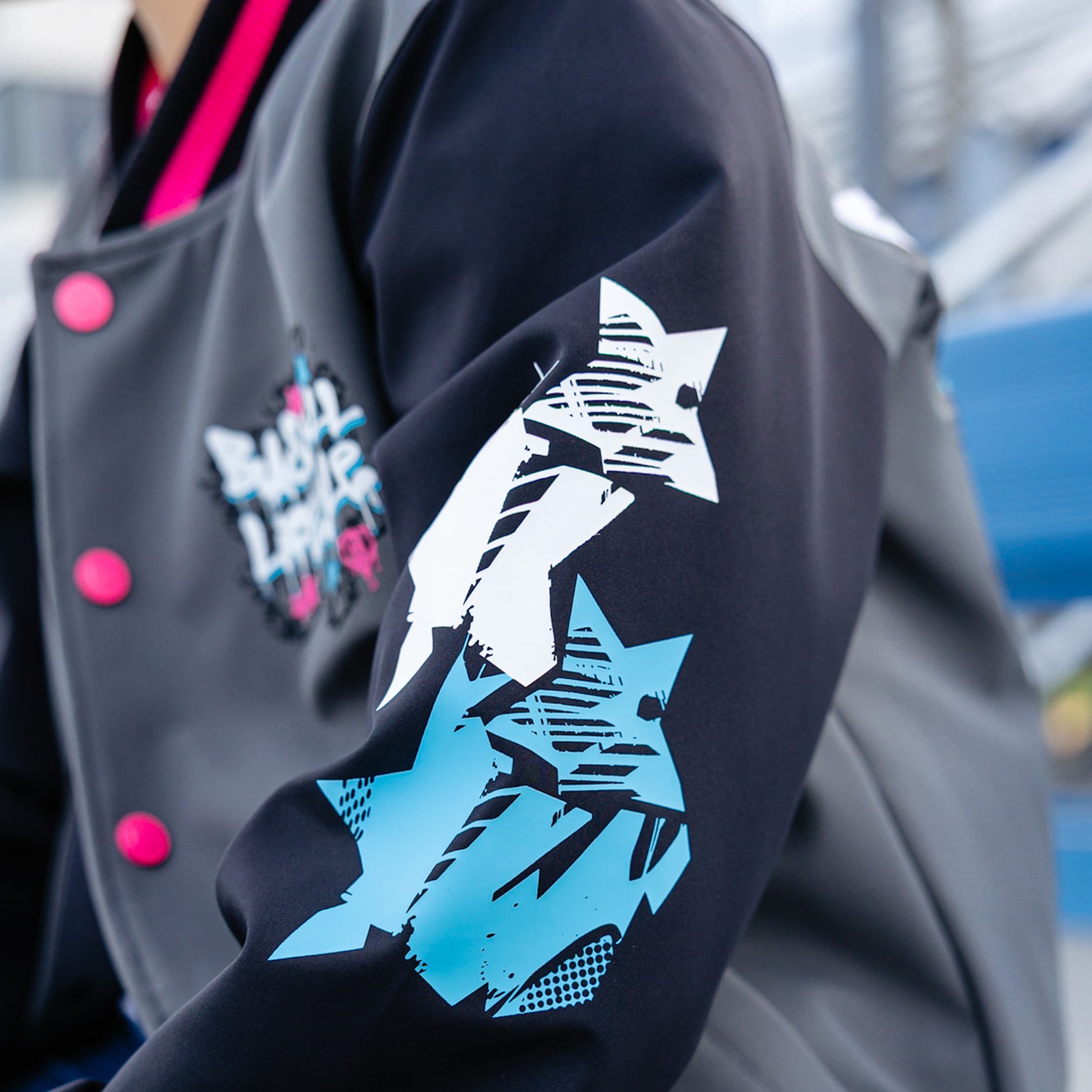 Gray and black jacket with star designs and pink buttons on a blurred background