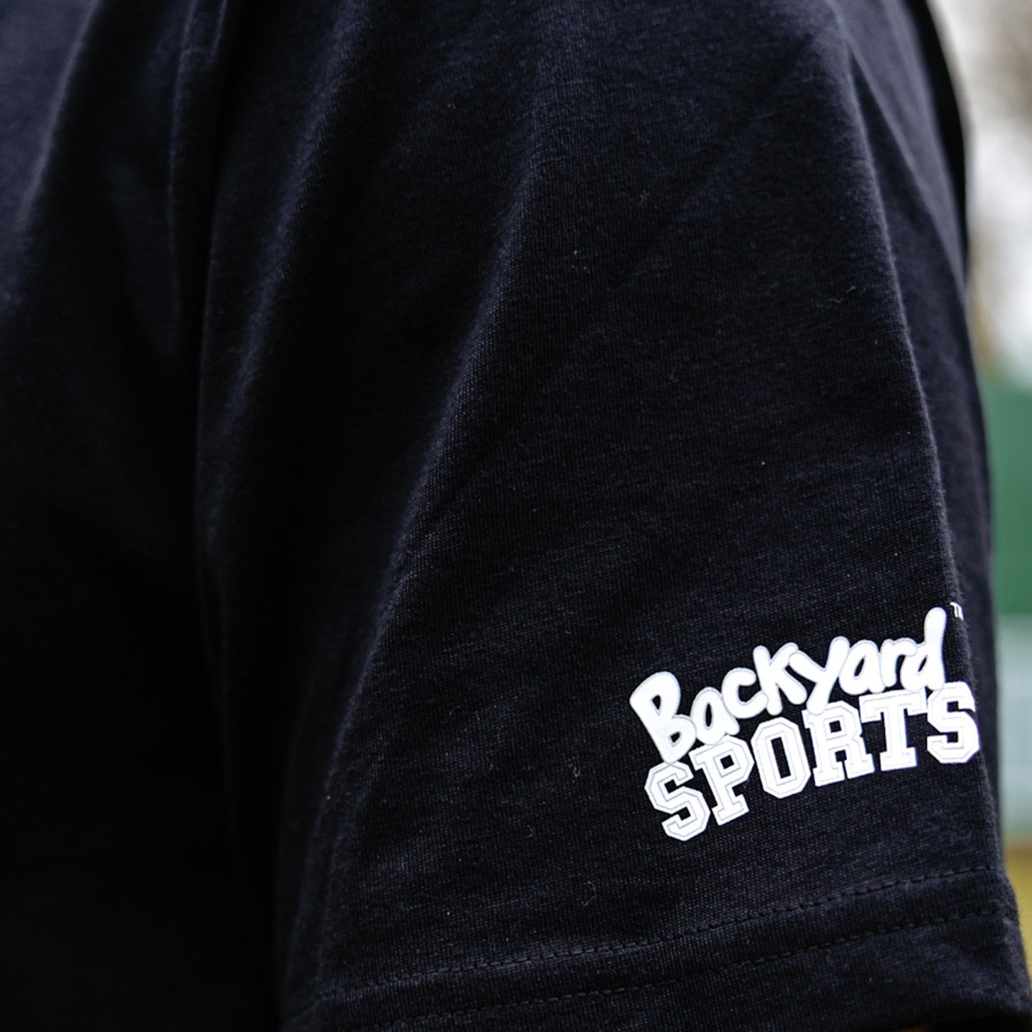close up of black t-shirt with 'Backyard Sports' logo on sleeve