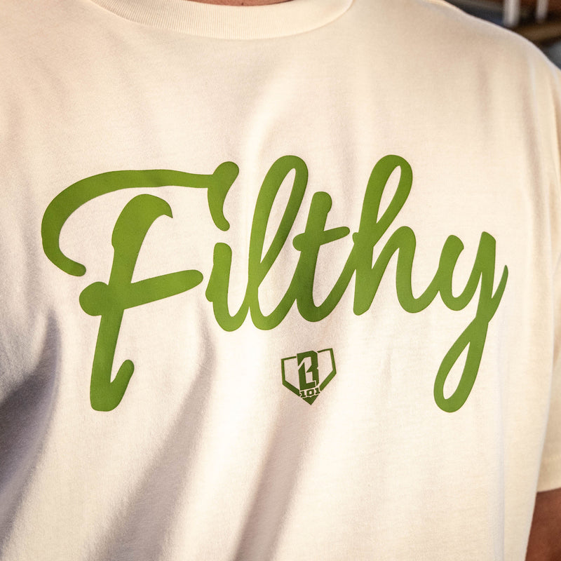 Close up of Youth Beige T-shirt with olive green ‘Filthy’ lettering and BL101 logo across chest.