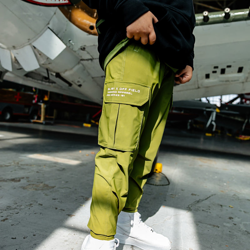 Olive green jogger cargo pants with drawstring waist, zippered pockets, utility cargo pockets, and white 'BL101 x OFF FIELD Training Apparel Pro Series' embroidered writing on side