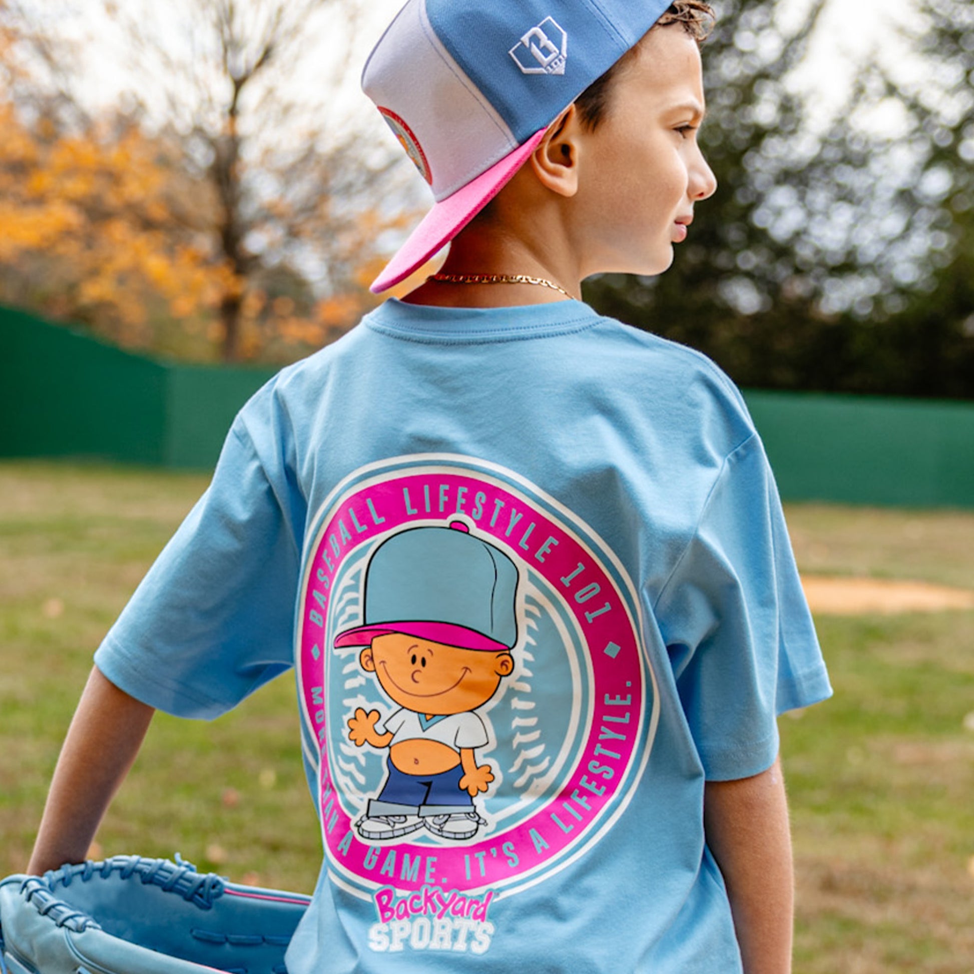 Child wearing a blue t-shirt with a Pablo Sanchez graphic design on back outdoors