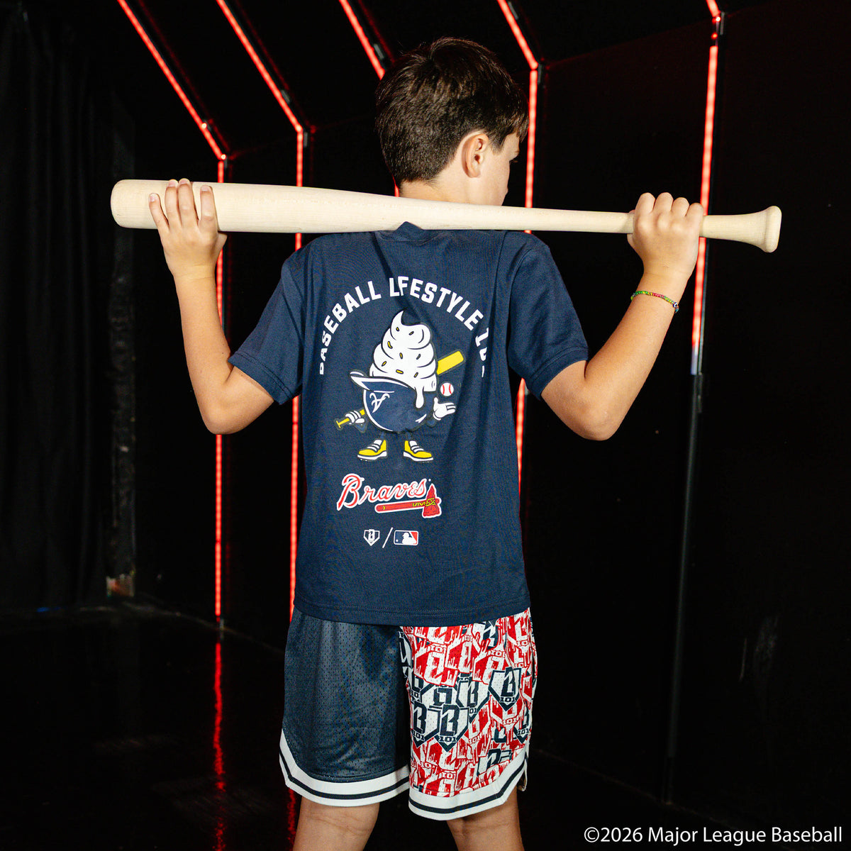 Youth model wearing navy youth shorts with "Atlanta Braves Sticker Court" design