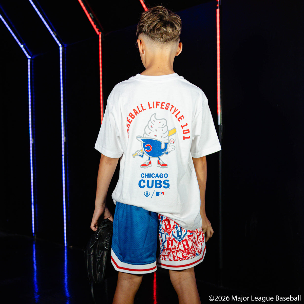 Youth model wearing blue youth shorts with "Chicago Cubs Sticker Court" design