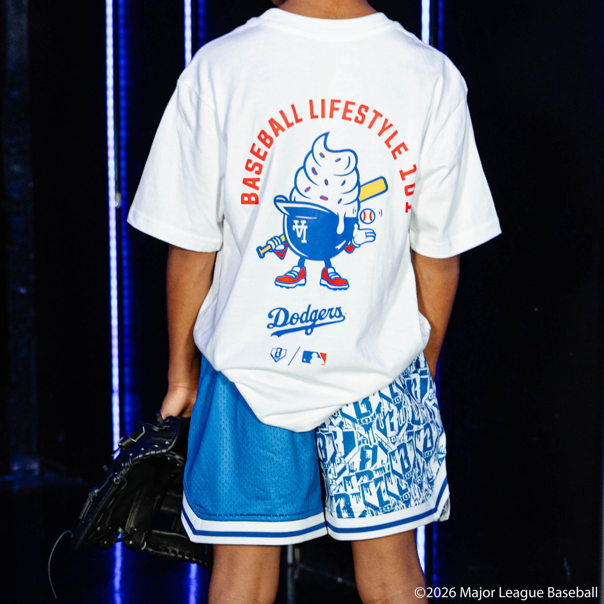Youth model wearing blue youth shorts with "Los Angeles Dodgers Sticker Court" design