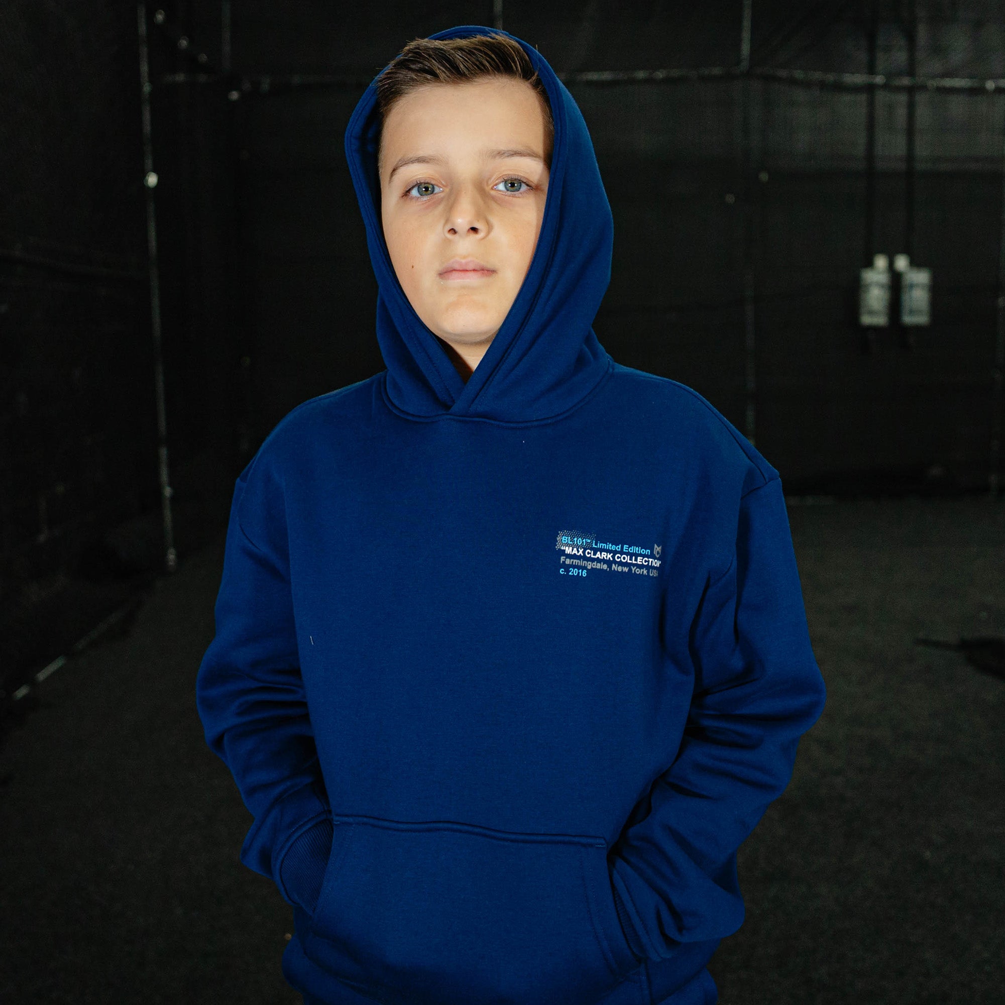 Person wearing a blue hoodie with a logo on a dark background
