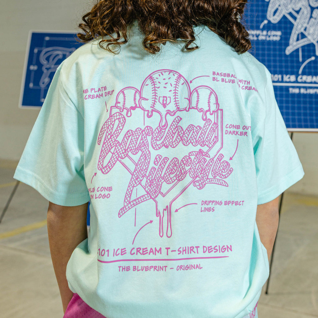 Person wearing a light blue t-shirt with pink ice cream graphic and "Baseball Lifestyle 101" logo