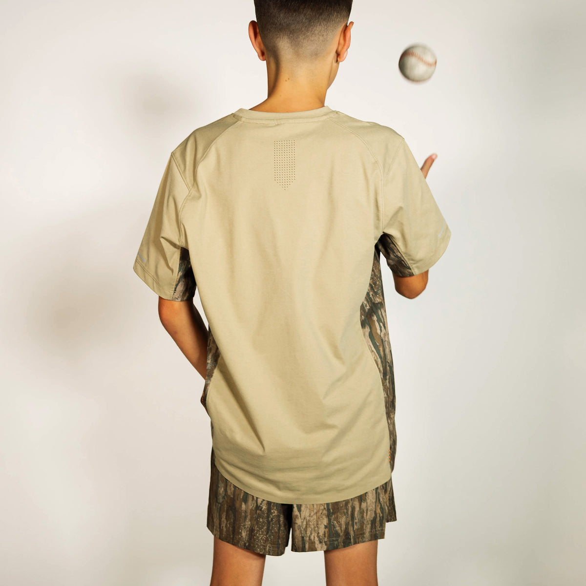 Youth model wearing multi-color Realtree Legacy Pro Series V2 Camo youth shorts with liner