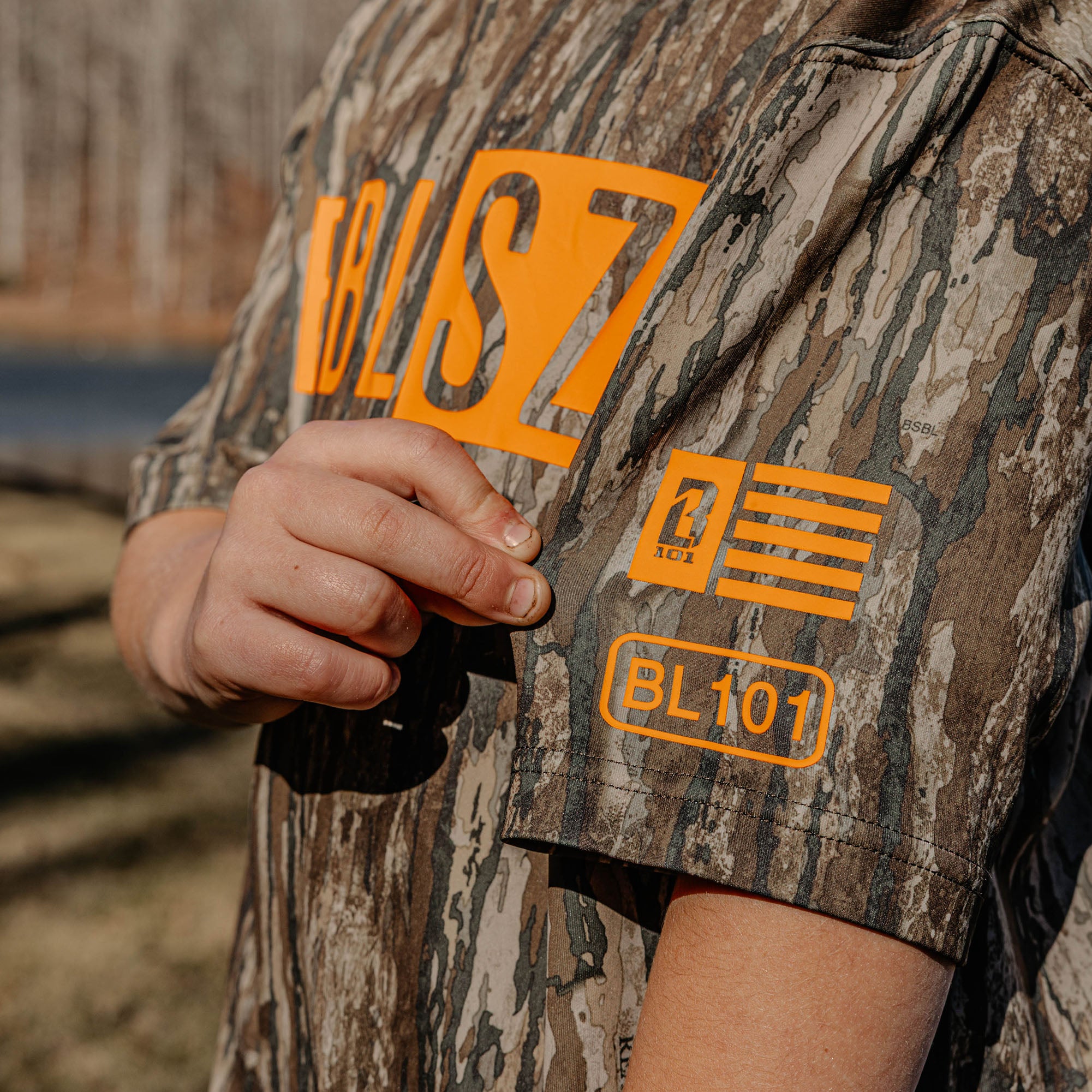 Camouflage shirt with orange 'BL101' logos in an outdoor setting