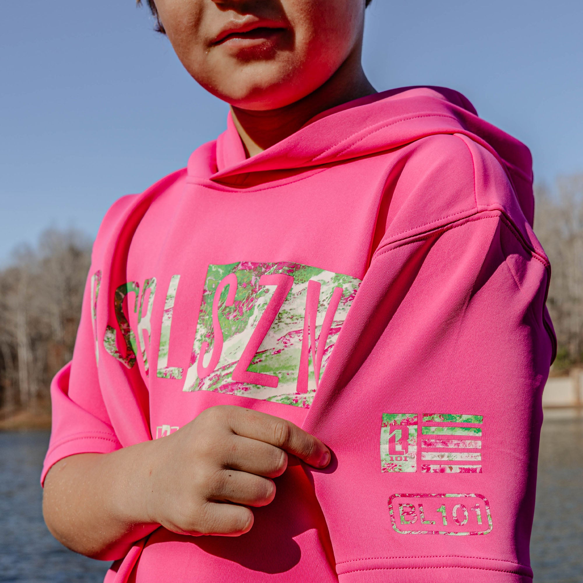 Person wearing a pink hoodie with pink and green BL101 logos outdoors