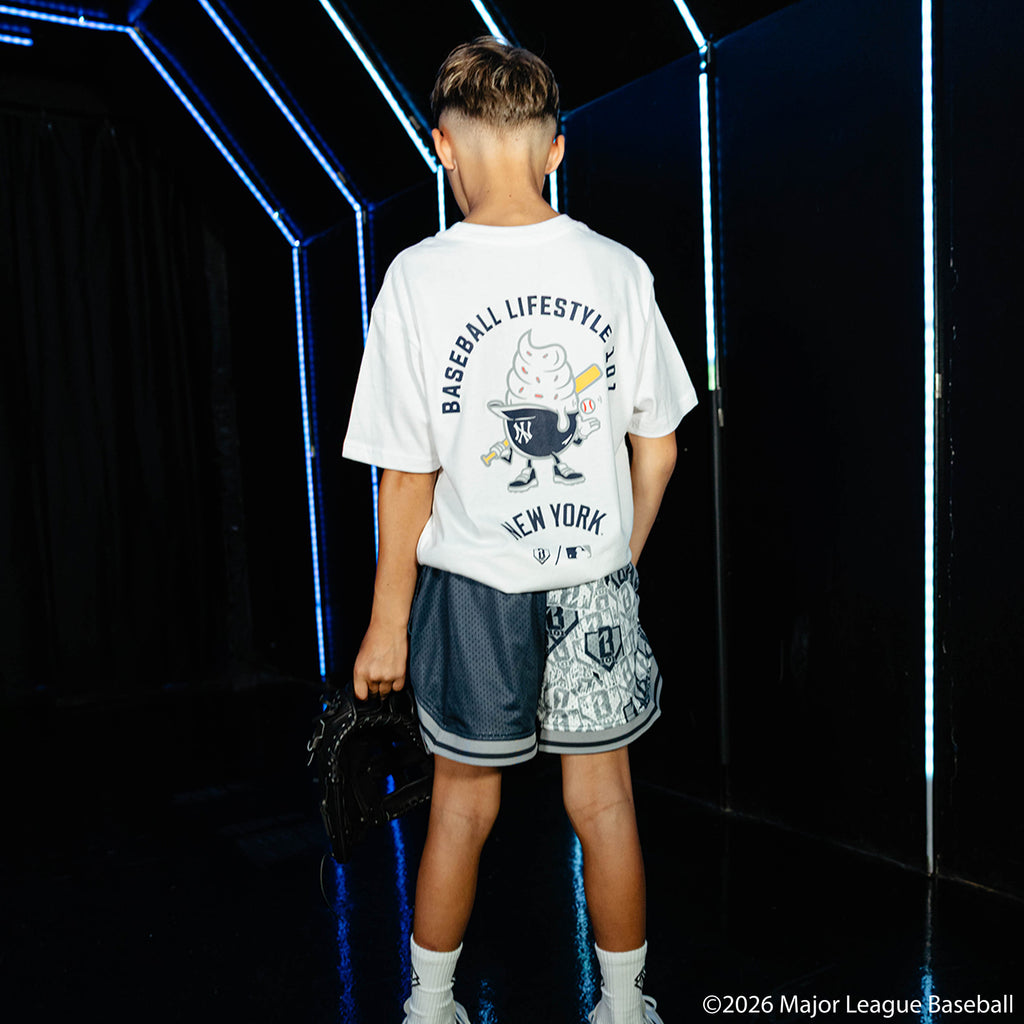 Youth model wearing navy youth shorts with "New York Yankees Sticker Court" design
