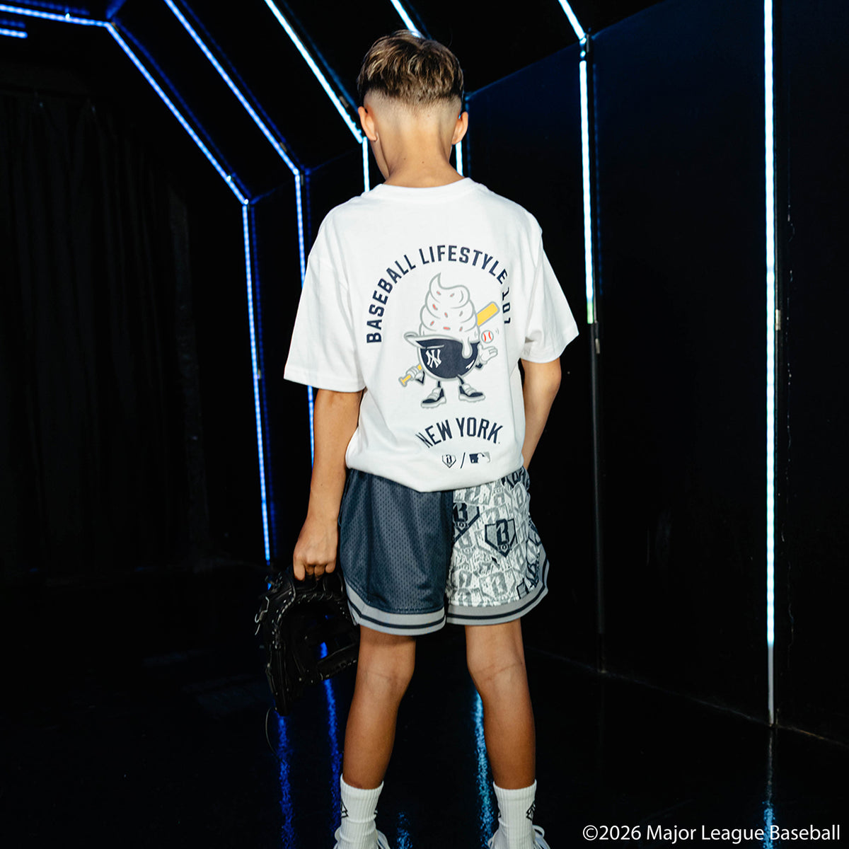 Youth model wearing navy youth shorts with "New York Yankees Sticker Court" design