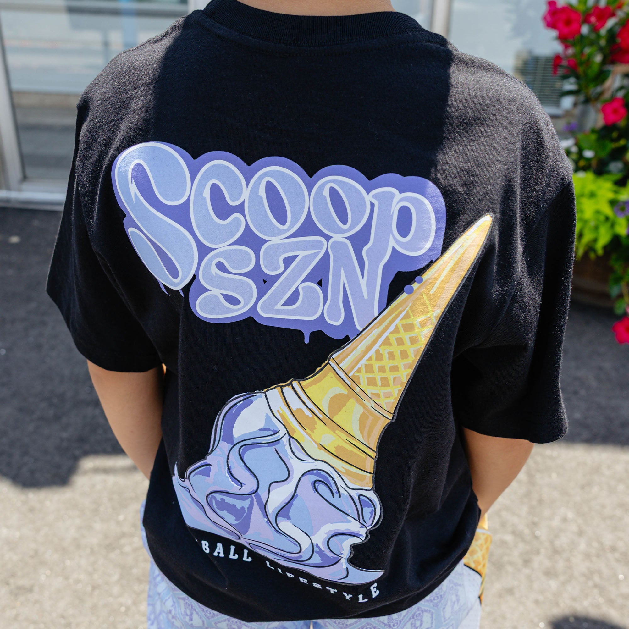 Youth model wearing youth graphic tee with "Scoop SZN" design