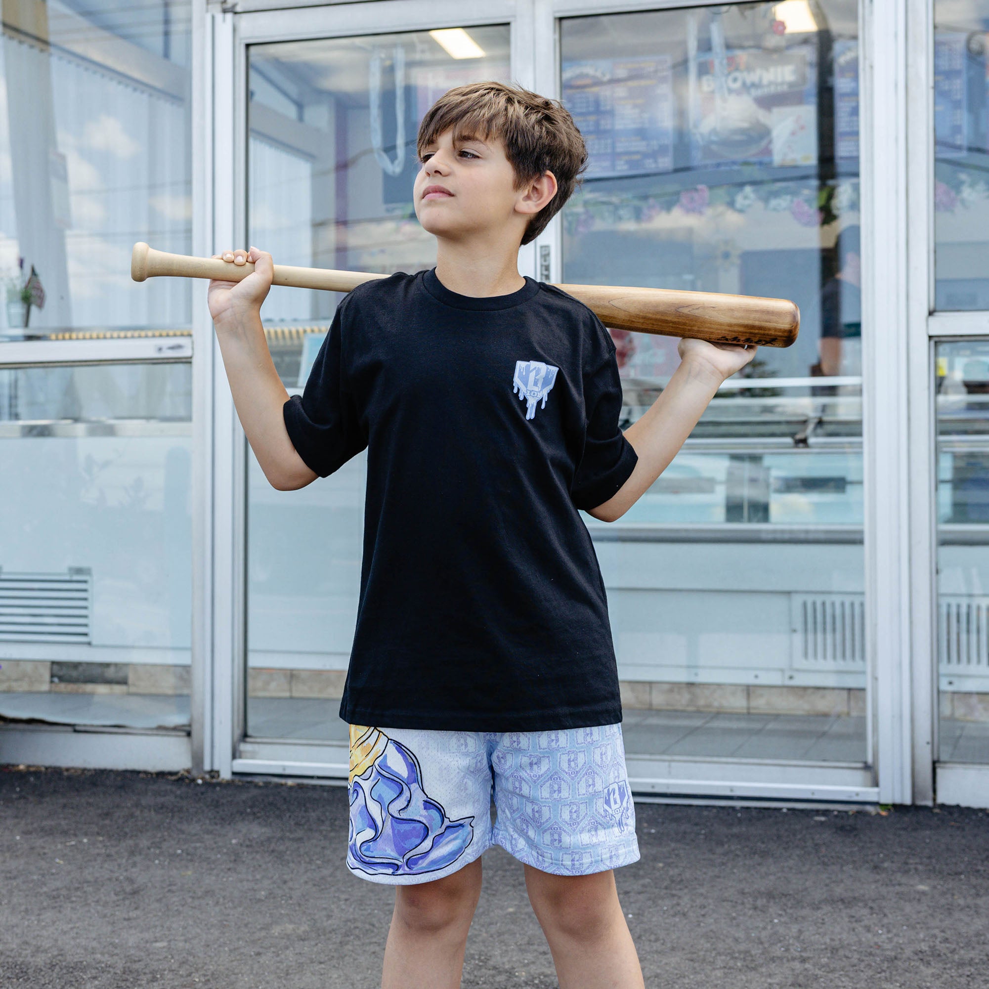 Youth model wearing youth shorts with "Scoop SZN" design