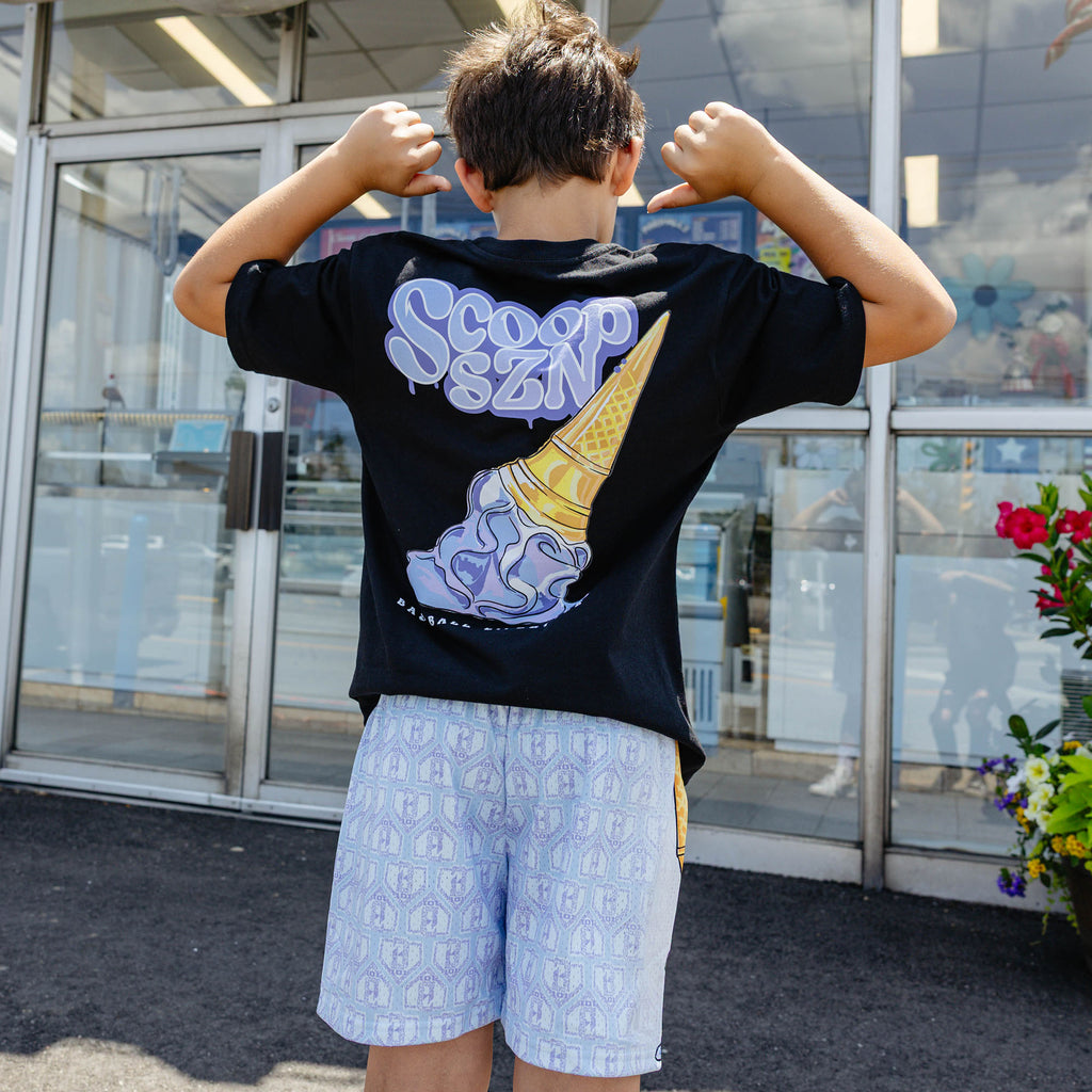 Youth model wearing youth shorts with "Scoop SZN" design