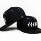 Side view of fitted black hat with white baseball stitching